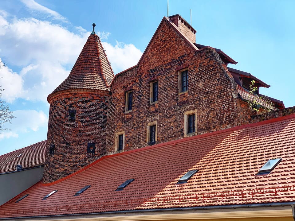 The Arsenal's round brick corner tower under a conical roof, against a blue sky.
