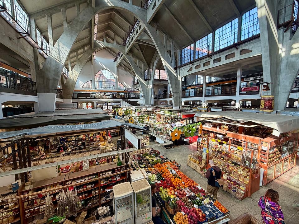 Inside the Market Hall: grey concrete arches rising over the fruit and grocery stalls.