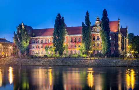 The National Museum lit at night, its long facade reflected in the Odra.
