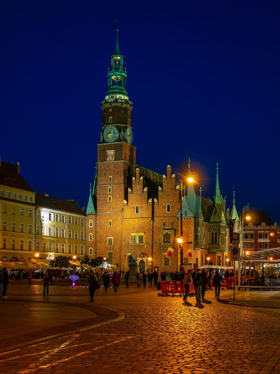 The Old Town Hall's brick tower and ornate east gable with its astronomical clock, lit at night against a dark blue sky.