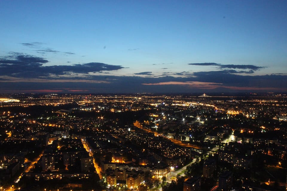 Wrocław from the Sky Tower after sunset: streets and blocks of flats lit below, and a last band of light along the horizon under a deep blue sky.