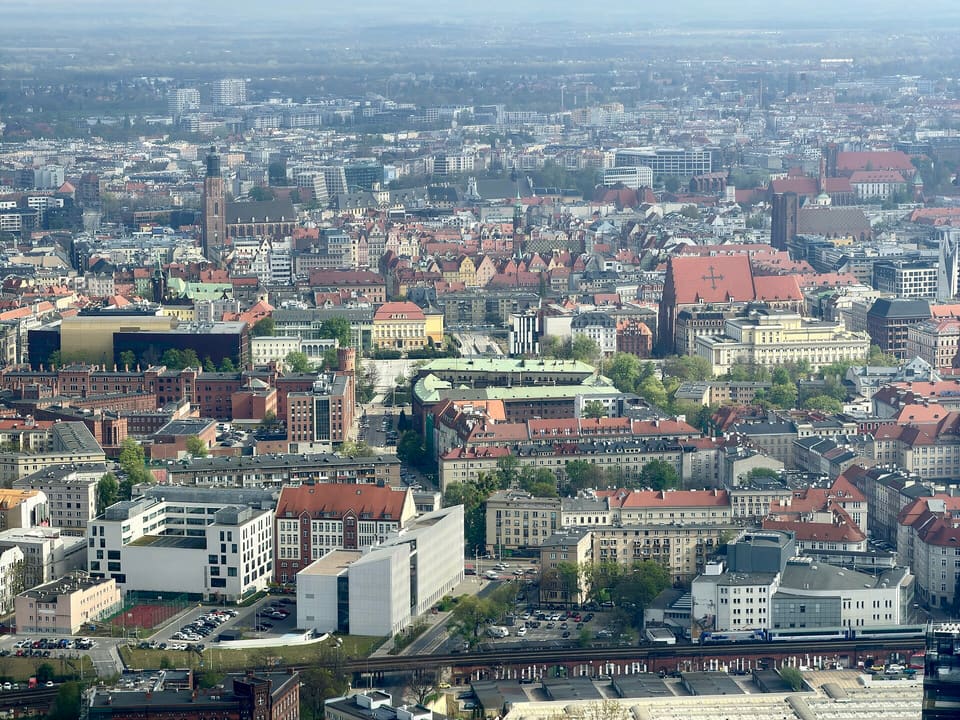 A view from the observation deck over the Old Town, with red-tiled roofs, church towers and spires below and the city stretching to a hazy horizon.
