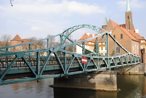 The green iron span of Most Tumski crossing a branch of the Odra.